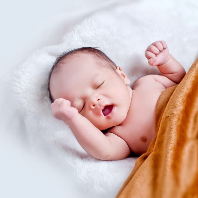 Nyfødt baby ligger på ryggen og sover.