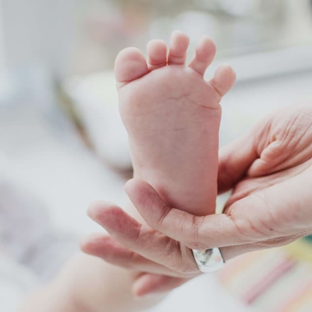En baby's fod bliver løftet i vejret.