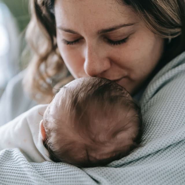 Mor står med baby i armene på vej til Børnefysioterapi.