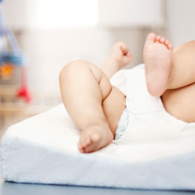 Baby ligger på ryggen med den ene fod i vejret.